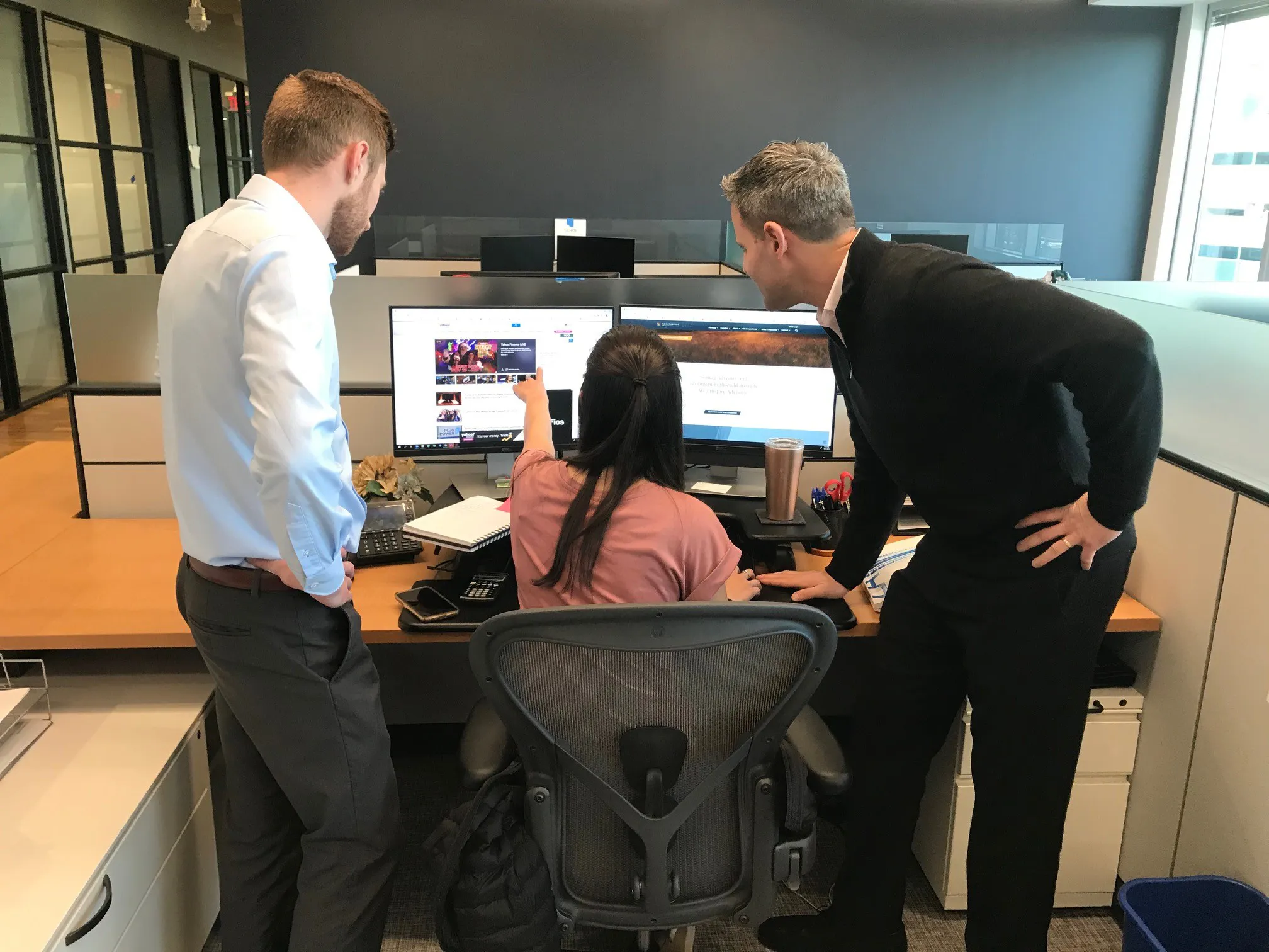 Coworkers standing looking at a monitor.