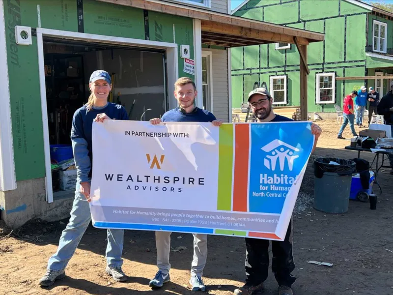 Coworkers holding a Habitat for Humanity banner.