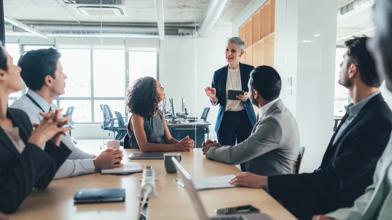 Woman leading a board meeting around a table.